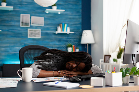 睡在客厅办公桌桌边的疲累工作主义黑人学生居家办公高清图片素材