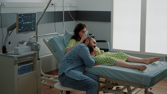 怀孕母亲用医疗设备躺在医院病房的床位上女士父亲母性保健诊所卫生病人婴儿男人孩子腹部高清图片素材