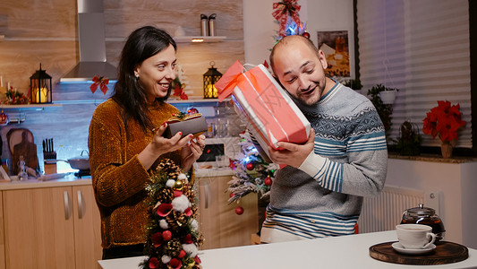 男人和女人互相赠送礼物盒 过圣诞节问候语新年交换丝带毛衣灯光伙伴厨房季节礼物背景图片
