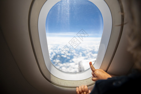 腰带云可爱的小孩在窗口中用手指指向天空 第一个飞行概念 与孩子们一起旅行 笑声航空公司运输腰带女孩班级飞机婴儿窗户乘客假期背景