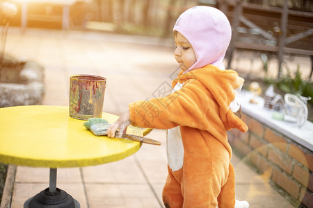 可爱的小小孩涂画黄色圆桌和刷子女孩童年乐趣男生绘画画笔艺术家幼儿园阳光女性有创造力的高清图片素材