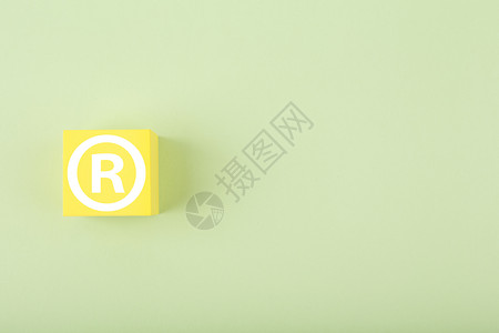 黄色玩具立方体上的白色商标标志 亮粉色绿色背景 带复制空间版权高清图片素材