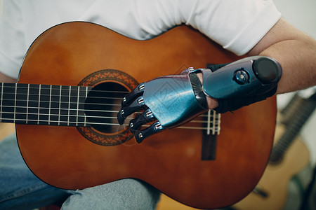 年轻残疾人在店里用人工假肢手 在吉他上弹琴音乐家高清图片素材