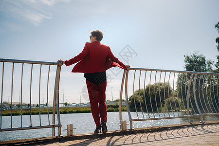 穿红西装的女孩站在湖边的码头上裤子男人外貌眼镜城市套装商业奢华街道商务背景图片