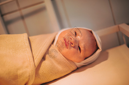 新生儿出生后包扎的婴儿躺在桌子上助产士高清图片素材
