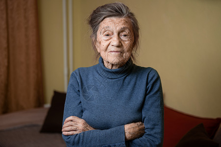 90 岁的可爱老妇人 头发花白 脸上有皱纹 穿着毛衣 肖像很大 微笑着 看起来很快乐 房间的背景 主题长肝抗衰 老人心情好疾病老背景图片