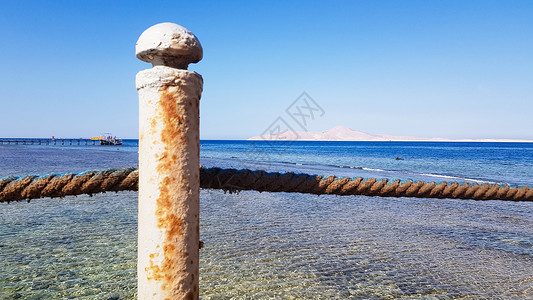 埃及红海的长浮桥 浮桥下降到水中 沙姆沙伊赫安利酒店领土上的木桥 上面有金属栅栏和海浪上的绳索海洋晴天天空行人热带旅行波浪旅游假背景