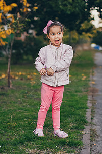 穿着粉红色夹克和粉红色短腿的小女孩 在公园里头发幸福微笑衣服公主喜悦裙子童年婴儿乐趣美丽高清图片素材