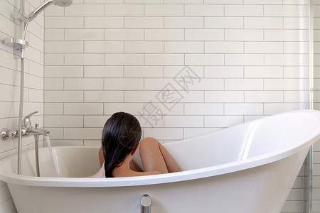 女人在洗浴间洗澡 在白色浴室背景图片