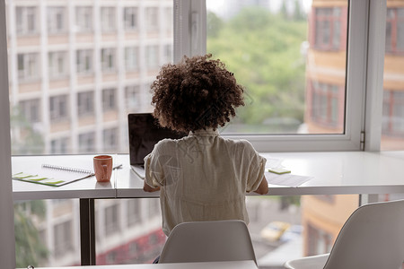 美国黑人年轻女工在工作时使用笔记本电脑背景