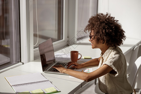 美国黑人非裔美国妇女集中关注计算机屏幕 以电脑屏幕为主代理人人士职业办公室房间桌子互联网工作笔记本记事本背景