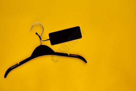 黑色礼品盒样机黑色衣架与黑色纸标签隔离在黄色纸背景上 服装标签 标签空白样机模板 用于放置您的设计 黑色星期五最终销售横幅背景