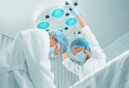 在手术室工作的外科医生男人手术医院女性治疗手套面具医师护士专家年轻的高清图片素材