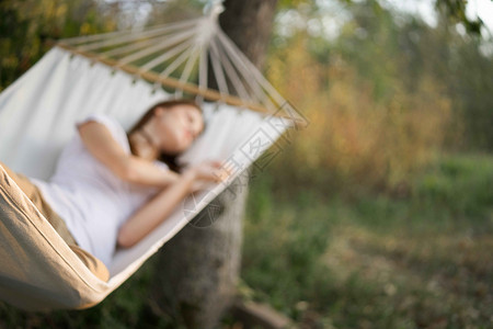 妇女睡在吊床室户外睡觉的休闲生活方式青少年旅行后院女性太阳休息室假期女士露台阴影树高清图片素材