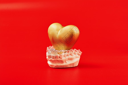牙齿形状红色背景中的金心在隐形牙齿矫正器或牙套中适用于正畸牙科治疗设备假牙宏观美学医生牙齿面罩口腔科面具诊所背景