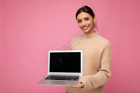 照片中美丽的年轻女子拿着电脑笔记本电脑 看着因背景多彩而隔绝的相机自由职业者学生神器社会监视器学习广告闲暇屏幕工作背景图片
