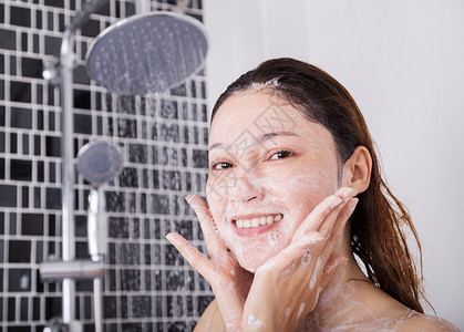 泡沫中的女孩在淋浴泡沫中洗脸的妇女女士皮肤微笑成人女孩享受温泉治疗酒店肥皂背景