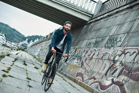 男人骑自行车年轻时尚男子骑自行车 在城市街道上 期待着微笑快乐的向前走动背景