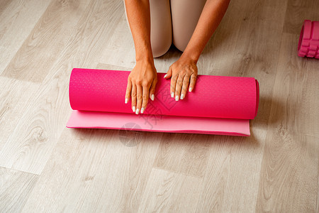 留着长头发的年轻女性 穿着米色运动服的健身教练 在健身房的瑜伽垫上做伸展运动和普拉提 女性健身瑜伽常规概念 健康的生活方式和谐与背景图片