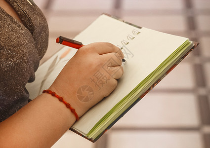 女孩的手拿着笔 在笔记本上写文字和设计特写写作职场报告教育桌子记事本女性文书备忘录铅笔概念高清图片素材