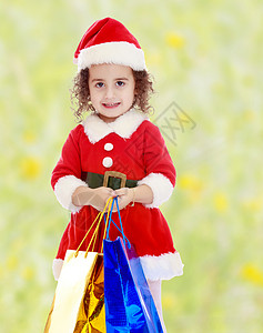 穿着圣诞老人装扮的小女孩 带着色彩多彩的包裹孩子们童年庆典婴儿季节礼物帽子乐趣喜悦幸福冬天高清图片素材