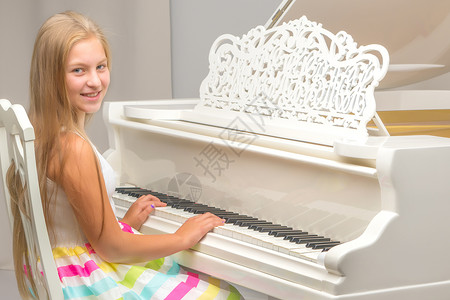 一个十几岁的女孩在弹白色大钢琴旋律艺术家学校钢琴家学院音乐会钥匙教育学习键盘实践高清图片素材