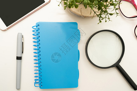 办公桌上的办公用品 包括键盘 眼镜和用于远程工作的咖啡杯 用于学习的各种学校公用设施 包括热饮和眼镜木头电脑视角蓝色桌子玻璃螺旋背景