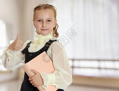 手头拿着一本书的女学生展示了拇指窗户幼儿园学生教育圆圈知识背包工作室女孩孩子宽敞高清图片素材