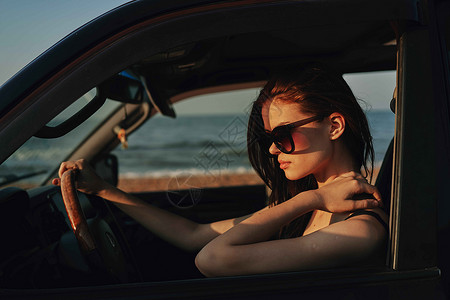 戴着太阳眼镜的开心女人 驾车出行旅行女性奢华窗户魅力眼镜汽车微笑女孩头发司机夏天高清图片素材