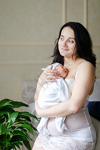 年轻美丽的母亲穿着白色衣服 怀着新生婴儿的身子背景图片