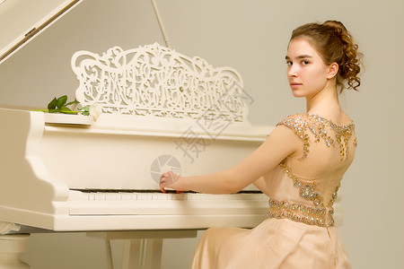 一个十几岁的女孩在弹白色大钢琴乐器学习仪器闲暇教育艺术家键盘学校学院训练美丽的高清图片素材