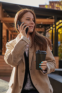 穿着时尚美衣的女人 用智能手机打电话 喝咖啡设备杯子青年咖啡成人晴天女士移动长发公共场所聊天高清图片素材