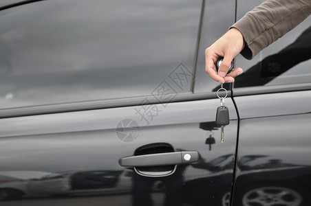 男性手持汽车钥匙 背景是新黑车高清图片