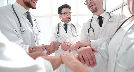 一群医生站在一个圆圈里站着精神联盟组织同事团体职员女性戒指男人病人友好的高清图片素材