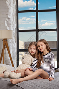 房间里两个小姐妹坐在床上的画面玩具孩子们卧室女孩女儿微笑寝具女郎快乐喜悦纯真高清图片素材