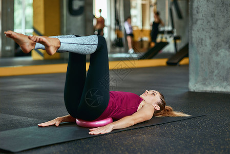 保持健康 身着运动服的年轻白人健身女性躺在健身房的瑜伽垫上 用小健身球做腹肌锻炼健康的高清图片素材