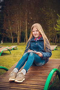 梦娃素材金发女孩写了一封信 坐在公园的木头雕像上背景