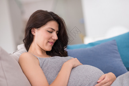 保持冷静等待在家沙发上坐着的孕妇母性闲暇成人女士怀孕生活母亲父母家庭房间背景