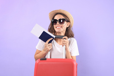 穿暑期临时服装的年轻旅游女孩 带太阳眼镜 红色手提箱 紫底护照和孤立的紫底护照女孩紫色女性商业假期手提包案件飞机飞机场冒险女士高清图片素材