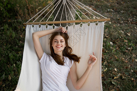 快乐的女人躺在一个吊床露天度假暑假的户外青少年旅行蓝色休息室地平线后院花园女孩露台假期全部高清图片素材
