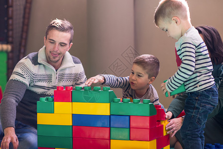一起来玩青少年家长和孩子们在儿童游戏室玩乐妈妈父母女士闲暇喜悦家庭孩子微笑享受母亲背景