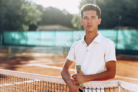 在网球场站着电击的年轻混种男子网球运动员混血红土人手老师男人教练法庭玩家运动背景图片