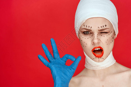 穿着蓝色手套针筒的漂亮女人 在脸上举红底脸部的轮廓上抬起红色背面皮肤护理塑料药品化妆品女孩医生成人女士嘴唇外科手术高清图片素材