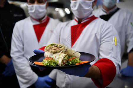 厨师口罩在冠状病毒新常态概念下 一群厨师戴着防护医用口罩和手套站在餐厅的厨房里卫生男性混血工作团体餐饮成人保健帽子烹饪背景