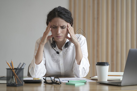 在家里办公室坐着时头痛按摩寺庙的有压力的创业妇女企业家 她们患有头痛疲劳的高清图片素材