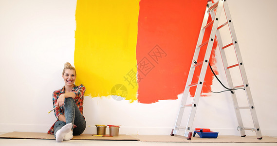 微笑墙坐在地板上的年轻女画家公寓装修微笑女孩设计师女郎绘画刷子维修工作背景
