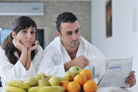 夫妻早餐看报纸早餐时在厨房看报纸快乐的一对情侣女士女孩成人杯子橙子男性乐趣黑发食物阅读背景