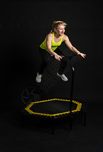 尽享人生身穿黄色 T 恤的黑色健身女健身蹦床上的女孩 运动型生活方式的有氧运动 体重弹跳 迷你健美操 年轻肌肉教练尽享背景
