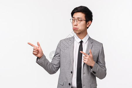 心烦意乱的亚洲年轻男性企业家失败 被解雇 情绪低落 情绪低落 叹气 指指点点 不安或沮丧 穿着灰色西装 白色背景的肖像领带高清图片素材