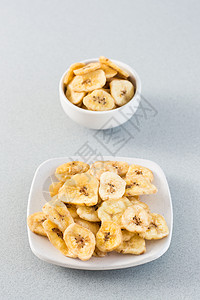 黄秋葵脆片白碗中烤香蕉薯片和桌上的碟子 快餐 网络横幅 垂直视图背景